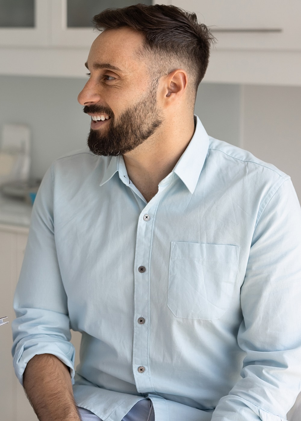 Man smiling in a light blue button-up shirt.