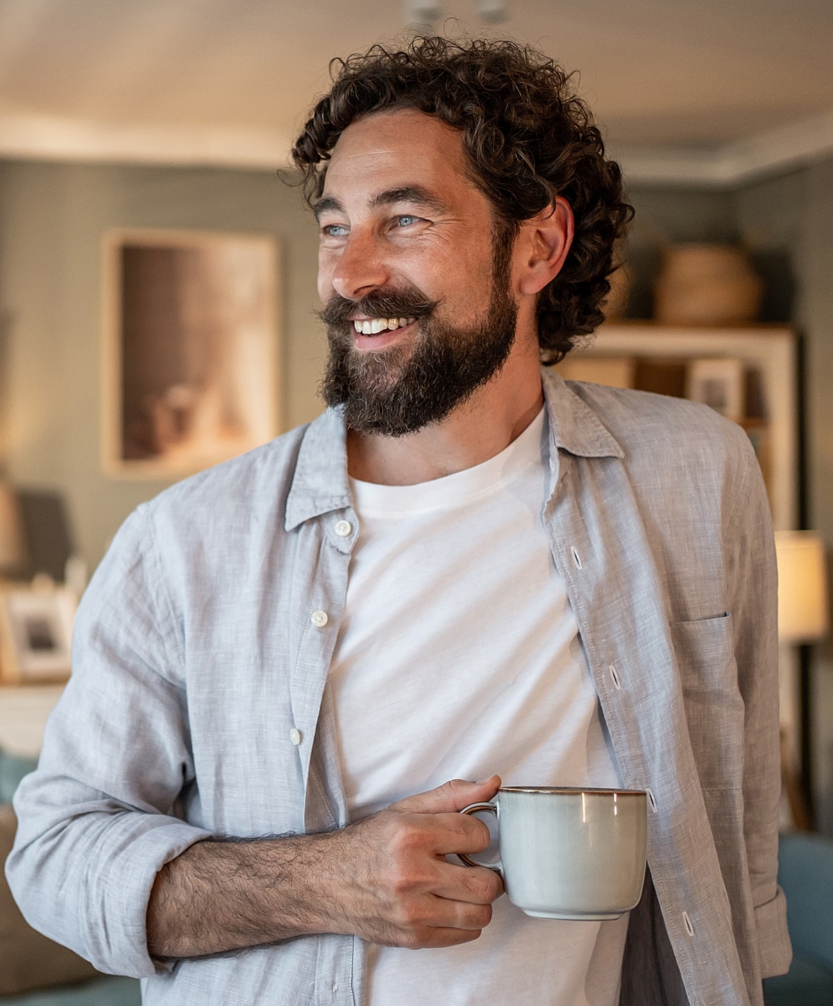 Man smiling with a coffee mug indoors.