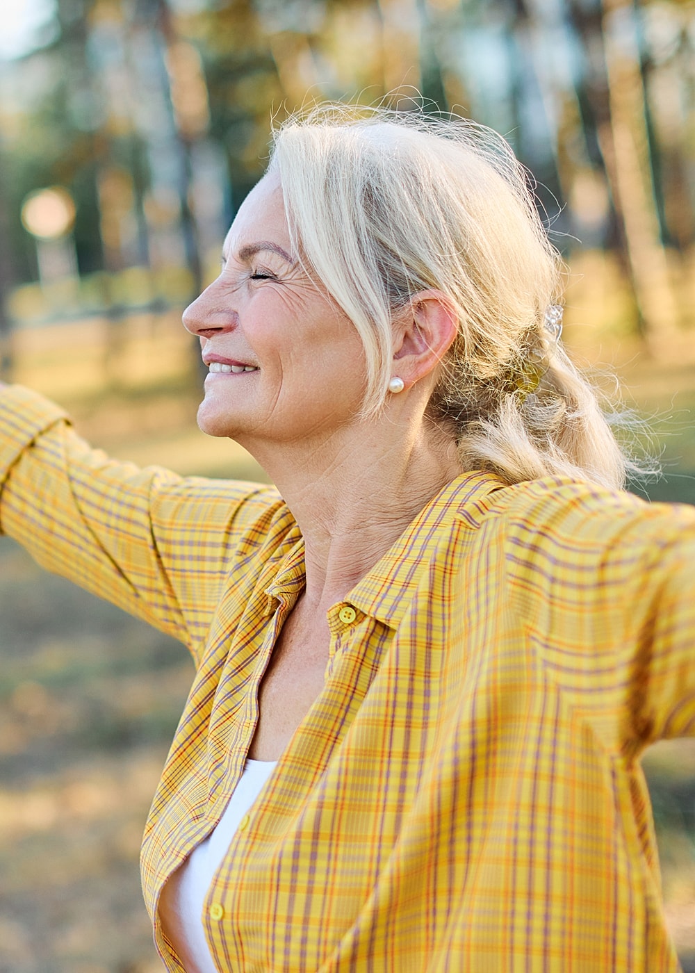 Smiling woman enjoying nature outdoors in sunlight.