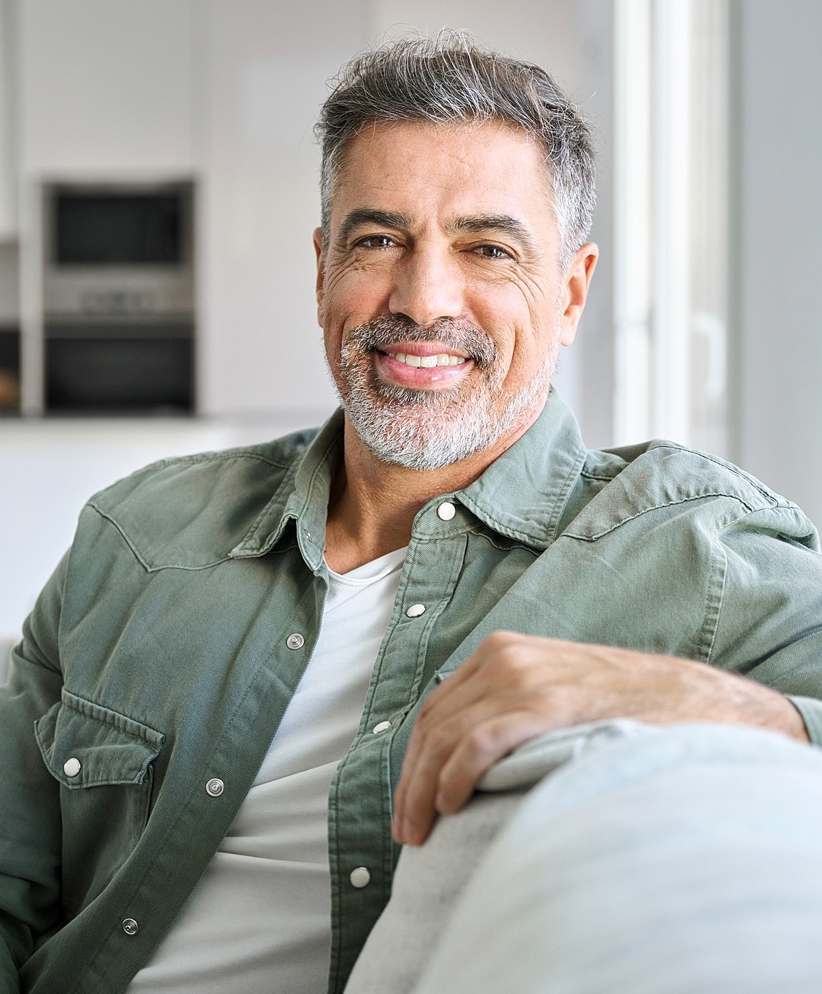 Smiling man sitting on a couch indoors.
