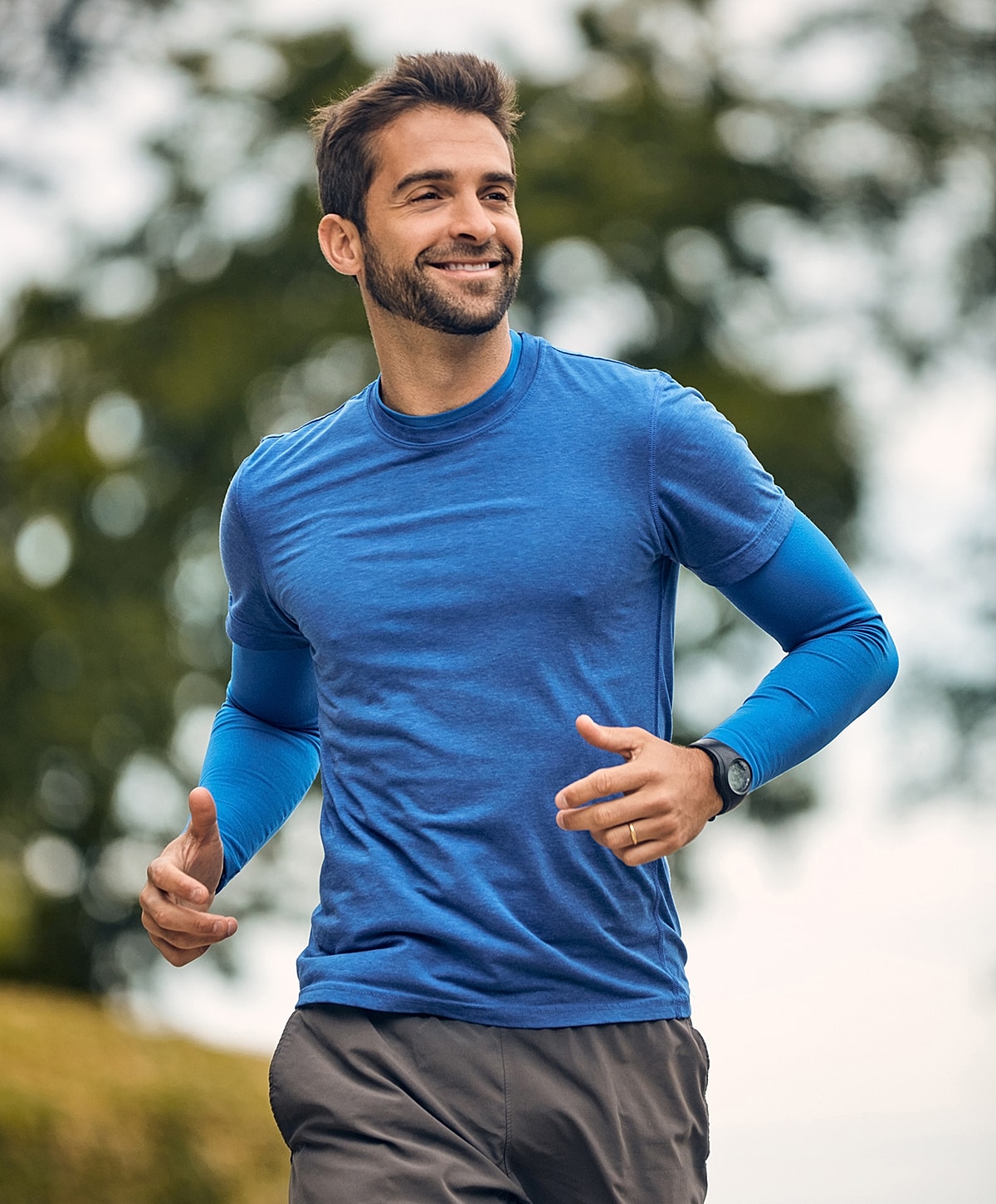 Smiling man jogging in blue athletic wear.
