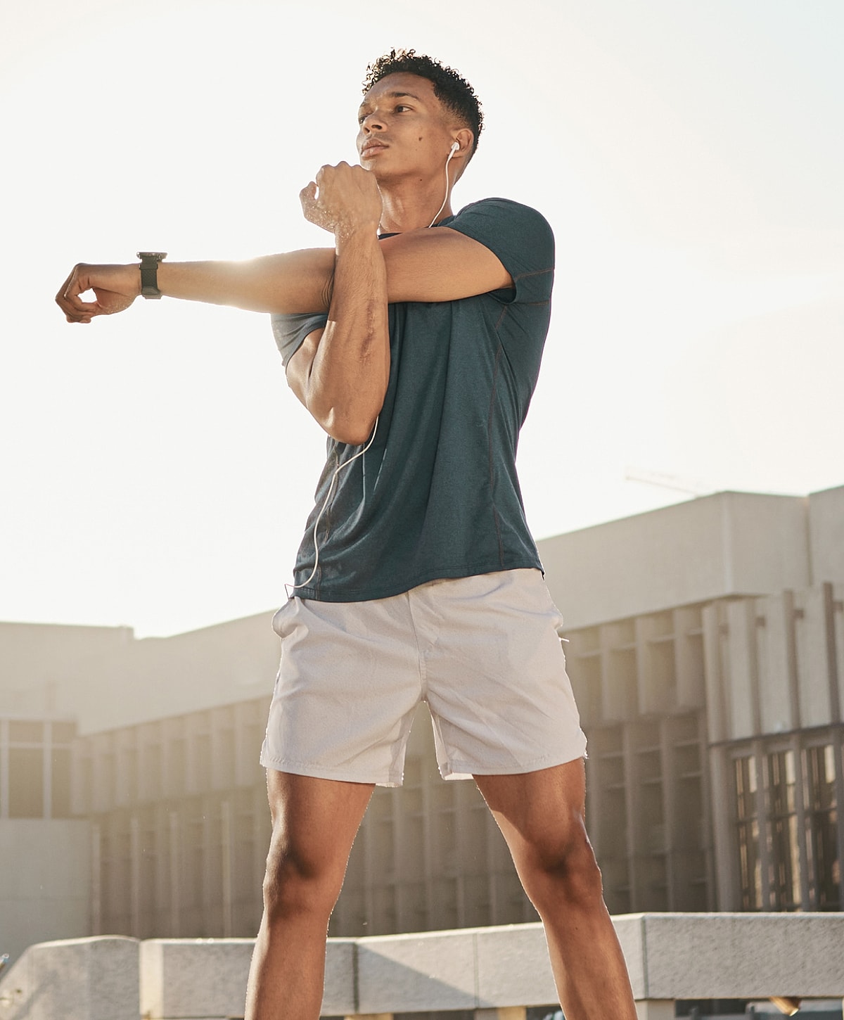 Man stretching outdoors with earbuds on.