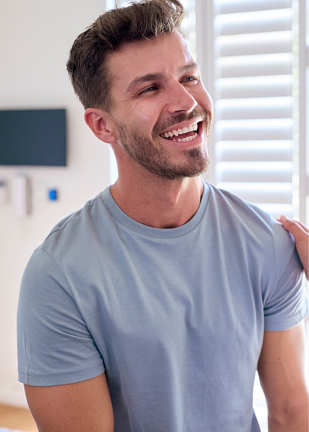 Smiling man in casual outfit, bright room.