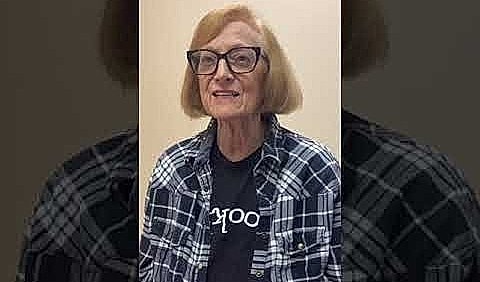 Older woman with glasses wearing a plaid shirt.