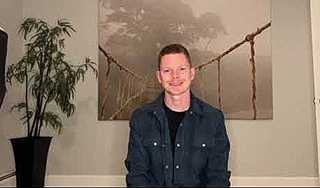 Person sitting in front of nature-themed backdrop.